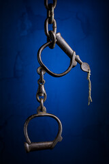 Old metal Handcuffs isolated on a blue textured background close-up.