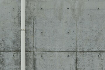 Concrete outer wall with a single white pipe