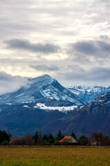 Fototapeta premium Varces et Allières France 11/2021 vue sur les montagnes enneigées, ciel orageux, nuageux, habitations au milieu des champs