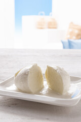 broken mozzarella on white square plate resting on white wooden table