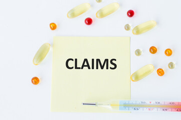 A card with text CLAIMS on a white background next to a thermometer and scattered multi-colored tablets