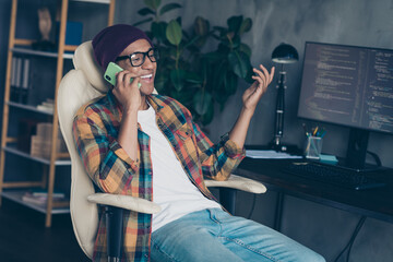 Photo of happy smiling freelancer wear hat glasses communicating modern device indoors workplace workstation loft