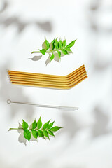 Eco friendly reusable stainless steel straws and cleaning brush on white background with hard light shadow, top view.
