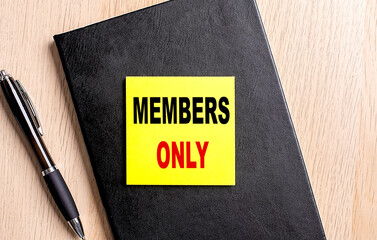 MEMBERS ONLY text on a sticky on black notebook with pen