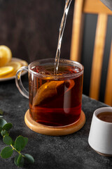 Black tea in glass cup, morning hot drink. Tea bag. Lifestyle, moody photo