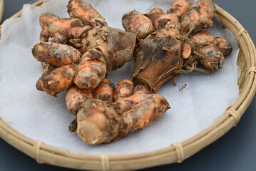 Fresh orange turmeric on a bamboo plate.