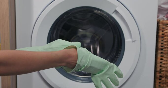 Applying rubber gloves against the backdrop of a washing machine.