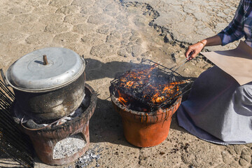woman's hand is grilling fresh sea fish on burning coals
