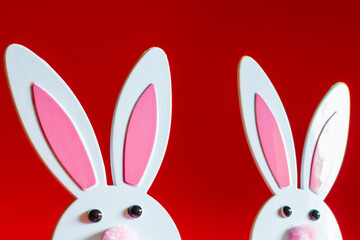 Fototapeta premium Two Toy Rabbit Bunny symbol of new year 2023 on red background.Christmas or New Year concept.Copy space.Closeup.