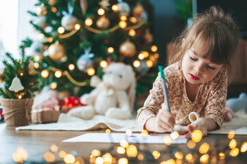 Cute little girl writing a letter to Santa Claus