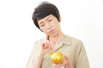 豚の貯金箱を持って悩む中年女性　白背景