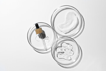 Many Petri dishes and cosmetic products on white background, top view
