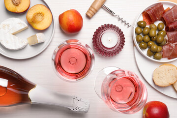 Delicious rose wine and snacks on white wooden table, flat lay