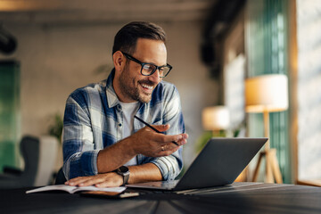 A man having an online meeting, sitting at the office, smiling and talking with one client.