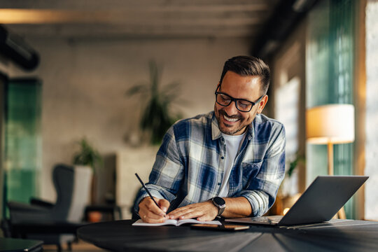 Smiling businessman making some notes, writing them in the noteb