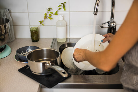Woman washing dishes in kitchen sink
