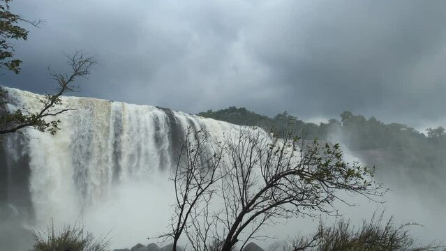 closeup of large beautiful waterfalls flowing strong and hard under scary rainclouds in the rainy season
