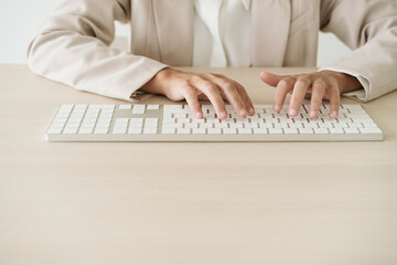 Close-up of businesswoman typing on keyboard at desk