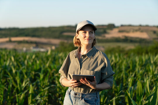 Woman standing with digital tablet in field looking around