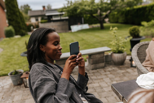 Smiling woman using phone in garden