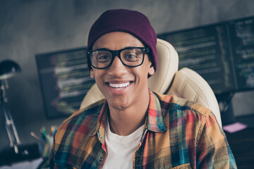 Photo of cheerful smiling guy dressed eyewear hat creating programming course indoors workstation workshop home