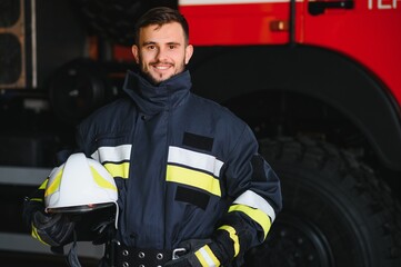 Fireman (firefighter) in action standing near a firetruck. Emergency safety. Protection, rescue from danger.