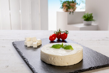 fresh cheese with basil leaf with tomatoes on a rectangular slate board set