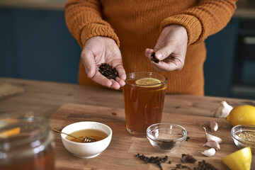 Close up of woman's hands adding cloves to the tea