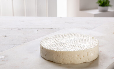 fresh cheese on white marble cutting board resting on wooden table, set