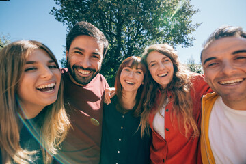 group portrait of smiling positive colorful friends having fun together outdoors in a sunny day - happy friendship concept