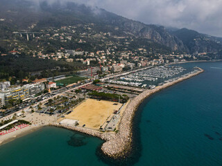 Aerial view of Menton in French Riviera from above. Drone view of France Cote d'Azur sand beach beneath the colorful old town of Menton. Small color houses near the border with Italy, Europe.