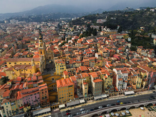Fototapeta na wymiar Aerial view of Menton in French Riviera from above. Drone view of France Cote d'Azur sand beach beneath the colorful old town of Menton. Small color houses near the border with Italy, Europe.