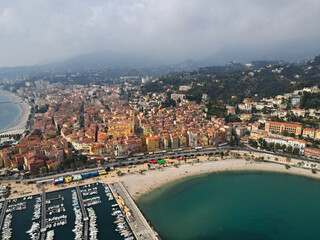 Fototapeta premium Aerial view of Menton in French Riviera from above. Drone view of France Cote d'Azur sand beach beneath the colorful old town of Menton. Small color houses near the border with Italy, Europe.