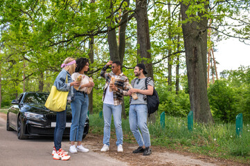 Group of young people standing in the forest near the car