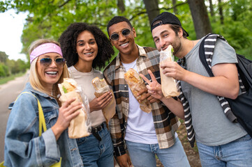 Young people eating sandwiches and looking joyful