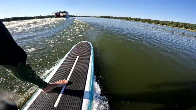 surfer on longboard in wave behind boat