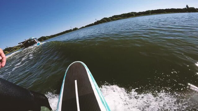 surfer on longboard in wave behind boat