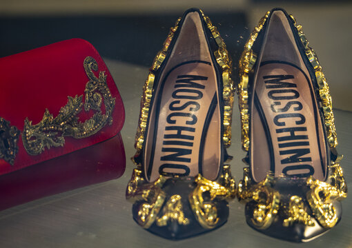 Red clutch bag and black pumps with golden details, luxury accessories by Moschino.Milan - Italy, 07 October 2022