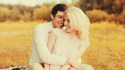Fototapeta premium Portrait of happy laughing young couple hugging on the grass in the park