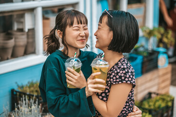 Two girls with lemonade in hands spending time together and looking happy