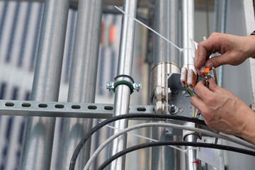 Electrical engineer connects wires to terminals, close-up hands