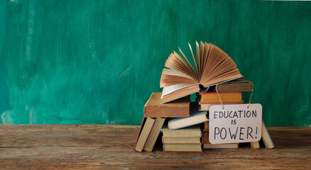 Open book, hardback books with education is power sign on teal...