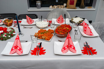 A table set before dinner for Christmas in Poland, visible baked fish fillets in a carrot salad and...