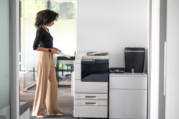 Woman in balck shirt and beige pants in the office looking determined