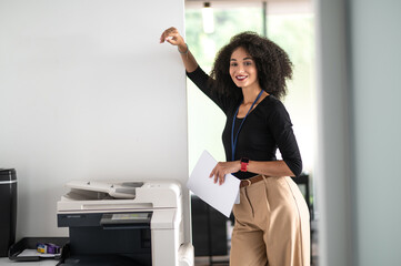 Confident good-looking young woman standing near xerox in the office