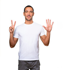 Fototapeta premium Happy young man doing a number seven gesture with his hands