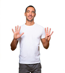 Happy young man doing a number nine gesture with his hands