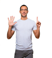 Fototapeta premium Happy young man doing a number six gesture with his hands
