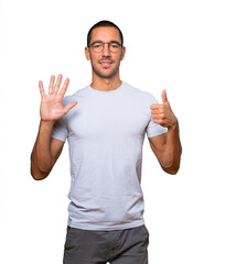 Happy young man doing a number six gesture with his hands