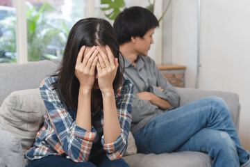 Family crisis. Asian wife crying on the sofa after husband cheating on her. - obrazy, fototapety, plakaty